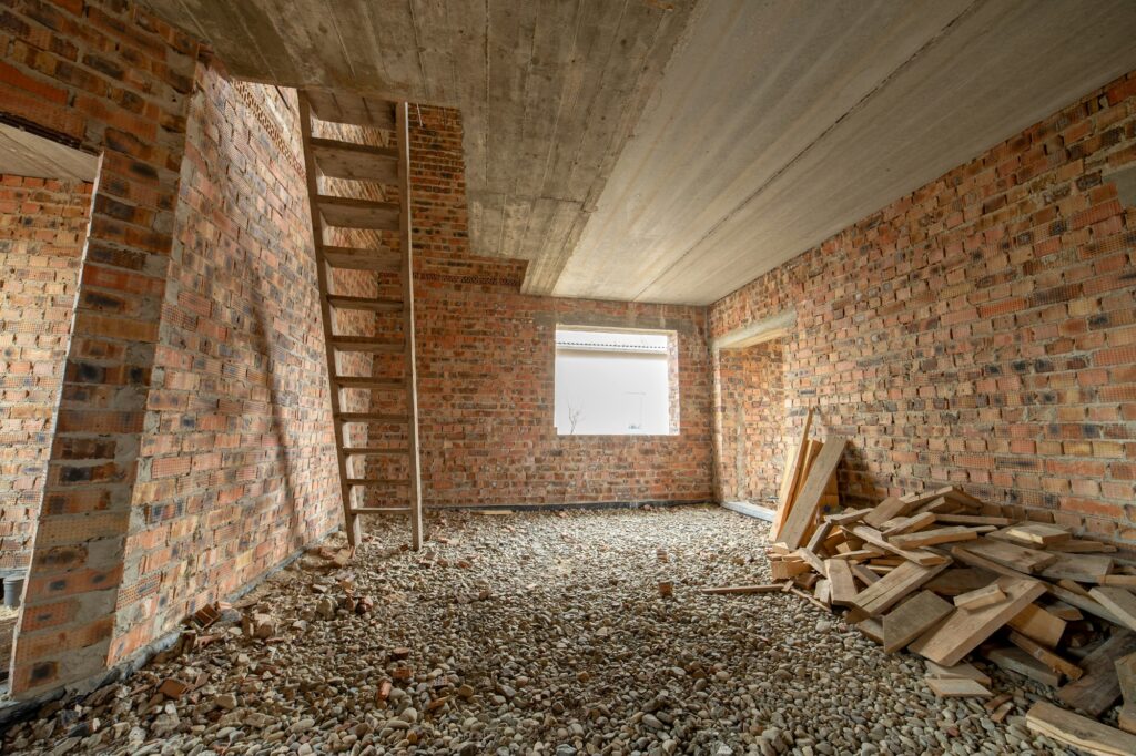 Interior of unfinished brick house with concrete floor and bare walls ready for plastering under
